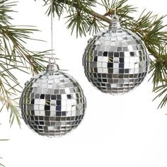 two disco ball ornaments hanging from a tree