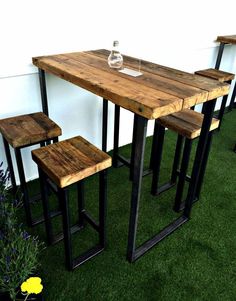 a wooden table sitting on top of a lush green field next to a white wall