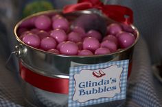 a metal bucket filled with pink chocolate eggs on top of a table next to a red ribbon