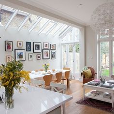 a living room filled with lots of furniture and pictures on the wall next to a dining table