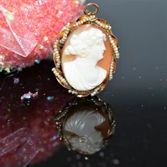 A ladies 14 karat yellow gold oval 1 inch by 1.25 inch shell cameo pin and pendant with a twisted ribbon border strung with seed pearls Pin Pendant, Pearl Brooch, Seed Pearl, Estate Jewelry, 1 Inch, Shells, Product Launch, Ribbon, Yellow Gold