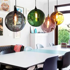 a dining room table with four hanging lights above it