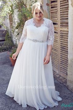 a woman in a white dress standing on the street with her hands in her pockets