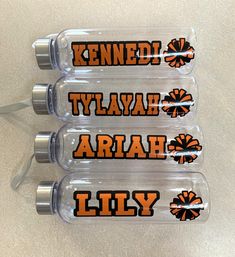 three personalized water bottles with orange and black cheerleaders on the side, sitting on a table