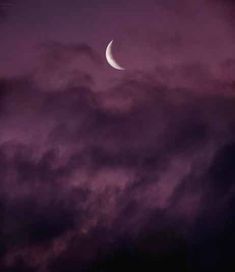 the moon is seen through some clouds at night