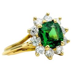 Ring Size: 6 This stunning ring showcases a vibrant green cushion-cut tsavorite gemstone, encircled by a glittering halo of diamonds, all set in warm and luxurious 18 karat yellow gold. The vivid green hue of the tsavorite is beautifully complemented by the brilliance of the surrounding diamonds, creating a captivating contrast that adds sophistication to any ensemble. Crafted with meticulous attention to detail, this ring exudes timeless elegance and glamour. The combination of the rich green t Luxury Tsavorite Ring Jewelry, Luxury Tsavorite Multi-stone Emerald Ring, Luxury Yellow Sapphire Multi-stone Jewelry, Luxury Yellow Sapphire Ring, Fine Jewelry, Luxury Multi-stone Tsavorite Gemstones, Split Shank Ring, Tsavorite Garnet, Green Cushions, Green Diamond