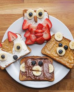 four pieces of toast on a plate with fruit and faces made to look like animals