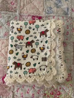 a quilted blanket with farm animals on it and fringe trimming around the edges