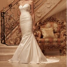 a woman standing in front of a staircase wearing a wedding dress with ruffles on the skirt