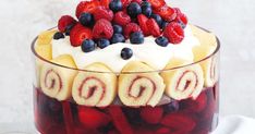 a trifle with berries and cream in a glass dish on a white tablecloth