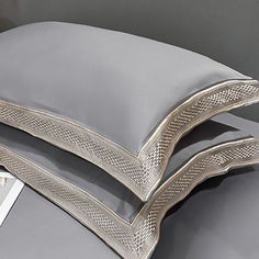 three pillows are stacked on top of each other in front of a gray bed sheet