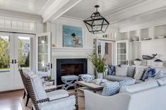 a living room filled with furniture and a fire place under a chandelier in front of a fireplace