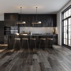 a modern kitchen with dark wood floors and black cabinets, along with bar stools