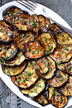 grilled eggplant and zucchini dish on a white platter with a fork