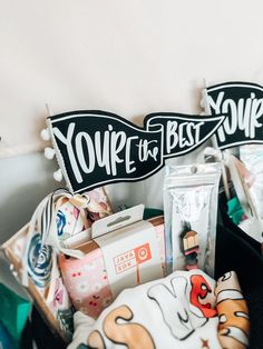 two black baskets filled with different types of items on top of a table next to signs that say you're the best stuff