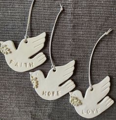 two white ceramic doves with the words faith, hope and love hanging from them