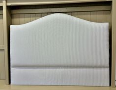 the headboard of a bed with blue and white striped sheets on it's sides