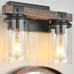 two light bathroom fixture with clear glass and wood accents on the wall above it's mirror