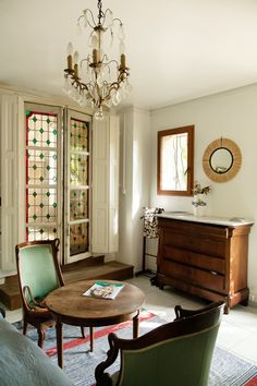 a living room filled with furniture and a chandelier hanging from the ceiling next to a window