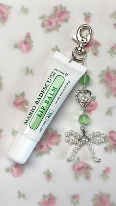 a tube of lip balm sitting on top of a keychain with a charm attached to it