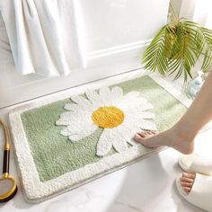 a person's feet on a bath mat next to a pair of scissors and a potted plant