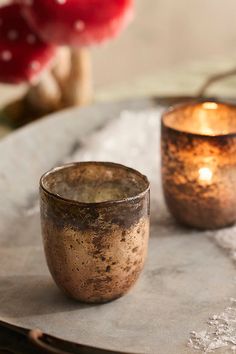 two candles sitting on top of a table next to each other in front of a mushroom