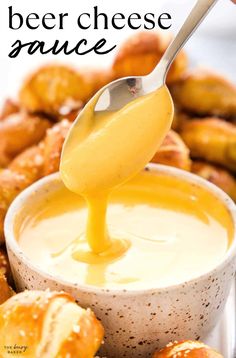 a spoon pouring cheese sauce into a bowl with pretzels in the background and text overlay that reads beer cheese sauce