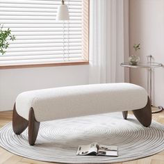 a white bench sitting on top of a rug in a living room next to a window