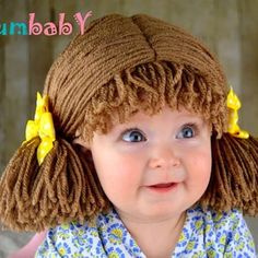 a baby girl wearing a brown wig with yellow flowers in her hair