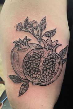 a pomegranate tattoo on the arm with leaves and flowers around it is black and white