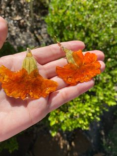 a person holding two orange leaves in their hand