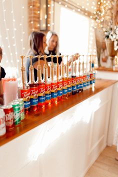 a woman standing behind a counter filled with drinks