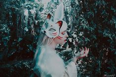 a woman wearing a white cat mask in the woods