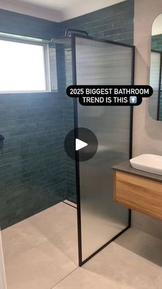 a bathroom with a walk in shower next to a white sink and wooden counter top