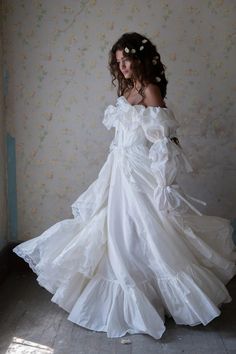 a woman wearing a white dress standing in front of a wall