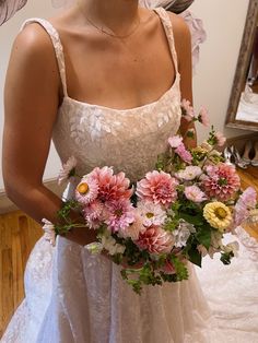 a woman wearing a wedding dress holding a bouquet of flowers in front of her face