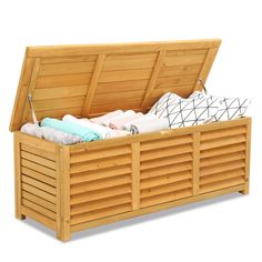 an open wooden storage box filled with blankets and pillows on top of it's sides