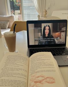 an open book sitting on top of a table next to a laptop computer and coffee cup