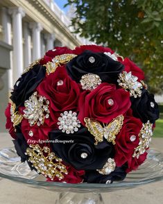 a bridal bouquet with black and red flowers in front of a white palace building