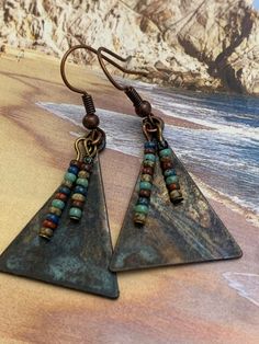 Copper and Glass Earrings. Triangular copper metal that has patina finish. Tiny earth multi-colored Czech glass beads adorn and dangle on the front. Unique handcrafted earrings. Sure to be your favorite pair! Highest Quality Craftmanship. Nickel-free Multicolor Copper Earrings, Multicolor Nickel-free Copper Earrings, Nickel-free Bronze Artsy Earrings, Artsy Brown Copper Jewelry, Artisan Copper Beaded Earrings Nickel Free, Bohemian Triangle Nickel-free Earrings, Unique Nickel-free Copper Beaded Earrings, Unique Copper Beaded Earrings Nickel Free, Nickel-free Bronze Beaded Copper Earrings