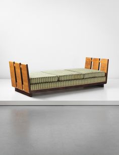 a wooden bed with green and white striped sheets on it's backrests