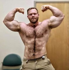 a shirtless man flexing his muscles in an office