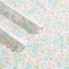 the fabric has flowers on it in pastel blue, pink and green colors with white background