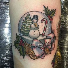 a snow globe with a snowman in it and holly wreaths on the side