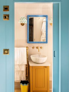 a bathroom with a sink and mirror on the wall next to a yellow trash can