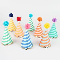 paper party hats with pom - poms on them are lined up against a white background