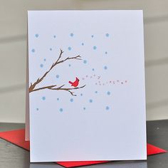 a christmas card with a red bird sitting on a branch and snowflakes in the background