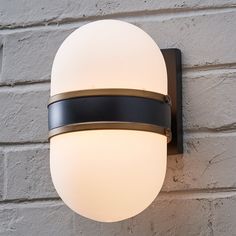 a white ball mounted on the side of a brick wall next to a light fixture