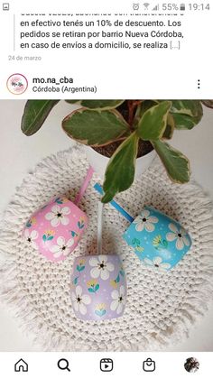 three painted rocks sitting on top of a white doily next to a potted plant