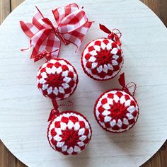 three red and white ornaments sitting on top of a wooden table next to a bow